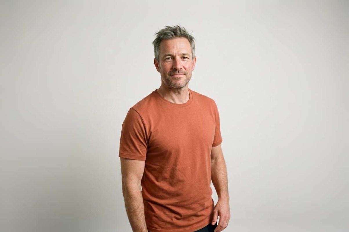 Homme grisonnant en t-shirt de sport terracotta sur fond studio clair — courbatures et reprise du sport, Pharmacie Charnal Quéven