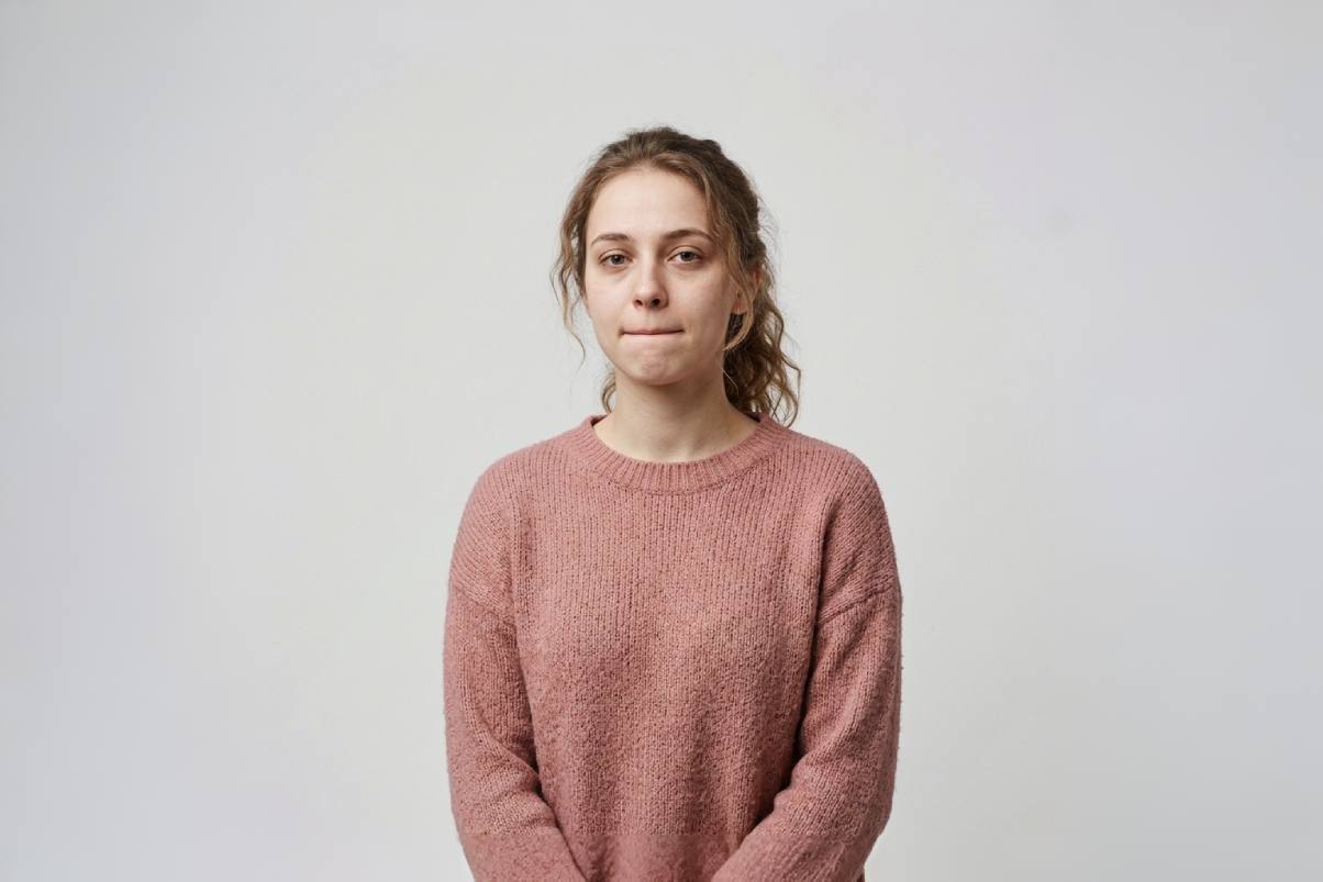 Jeune femme d'une vingtaine d'années en pull rose, expression fatiguée mais déterminée — stress des examens, Pharmacie Charnal Quéven