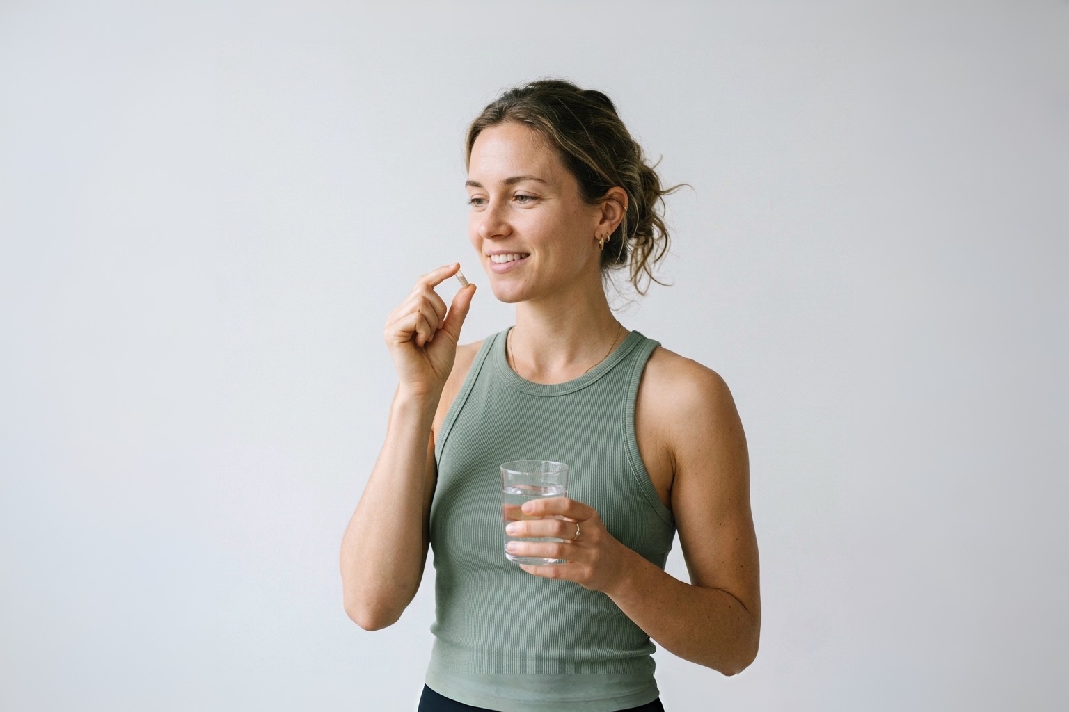 Jeune femme active prenant un probiotique avec un verre d'eau, conseils pour bien choisir sa souche, Pharmacie Charnal Quéven Bretagne